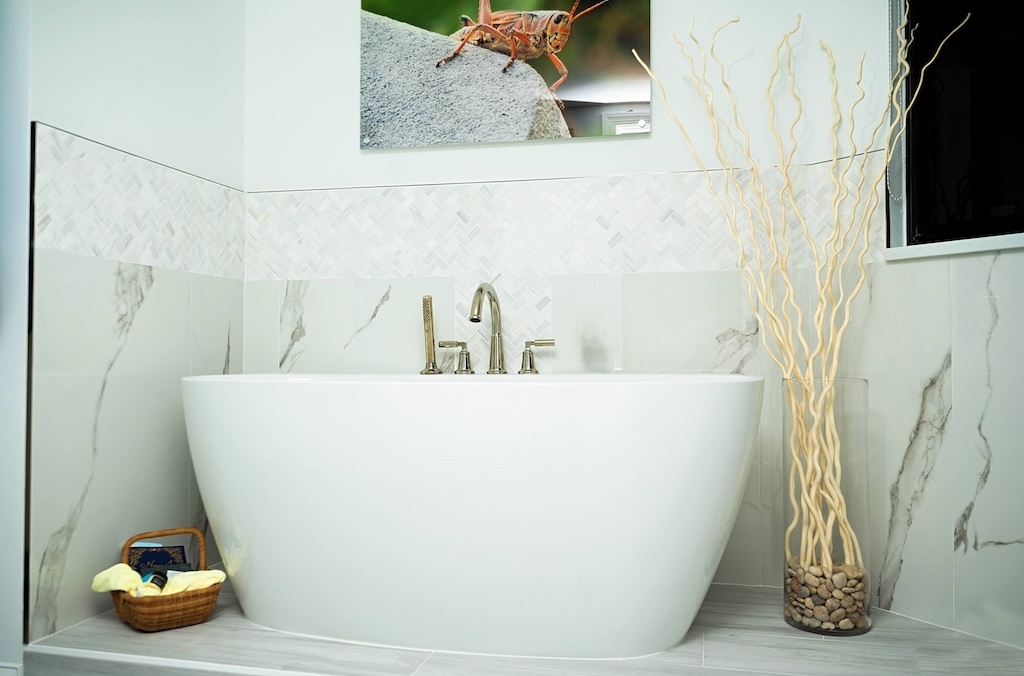 Primary bathroom remodel in Naples with freestanding tub and marble-look tile