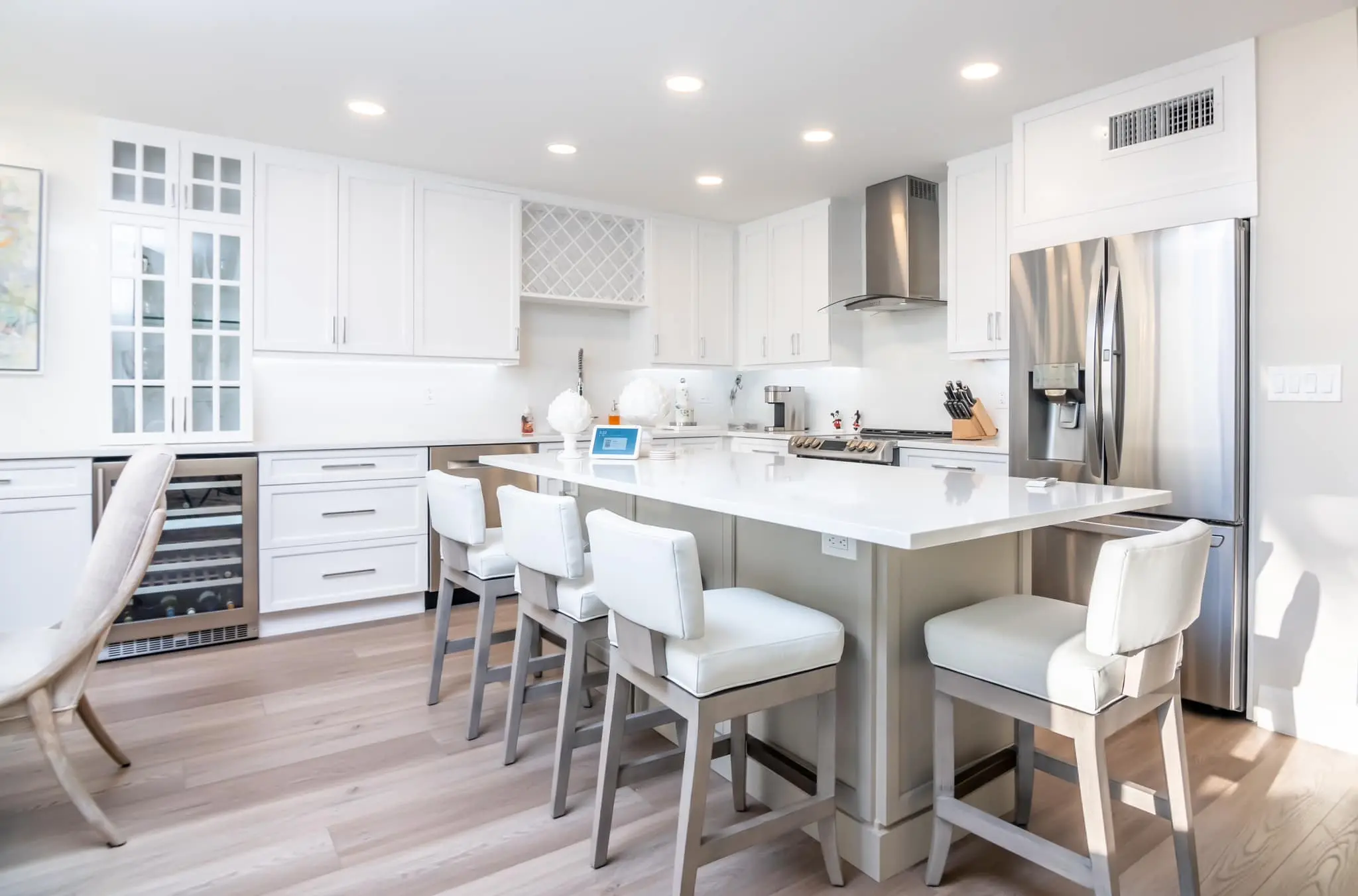 White kitchen with glass-front upper cabinets and island seating in Naples